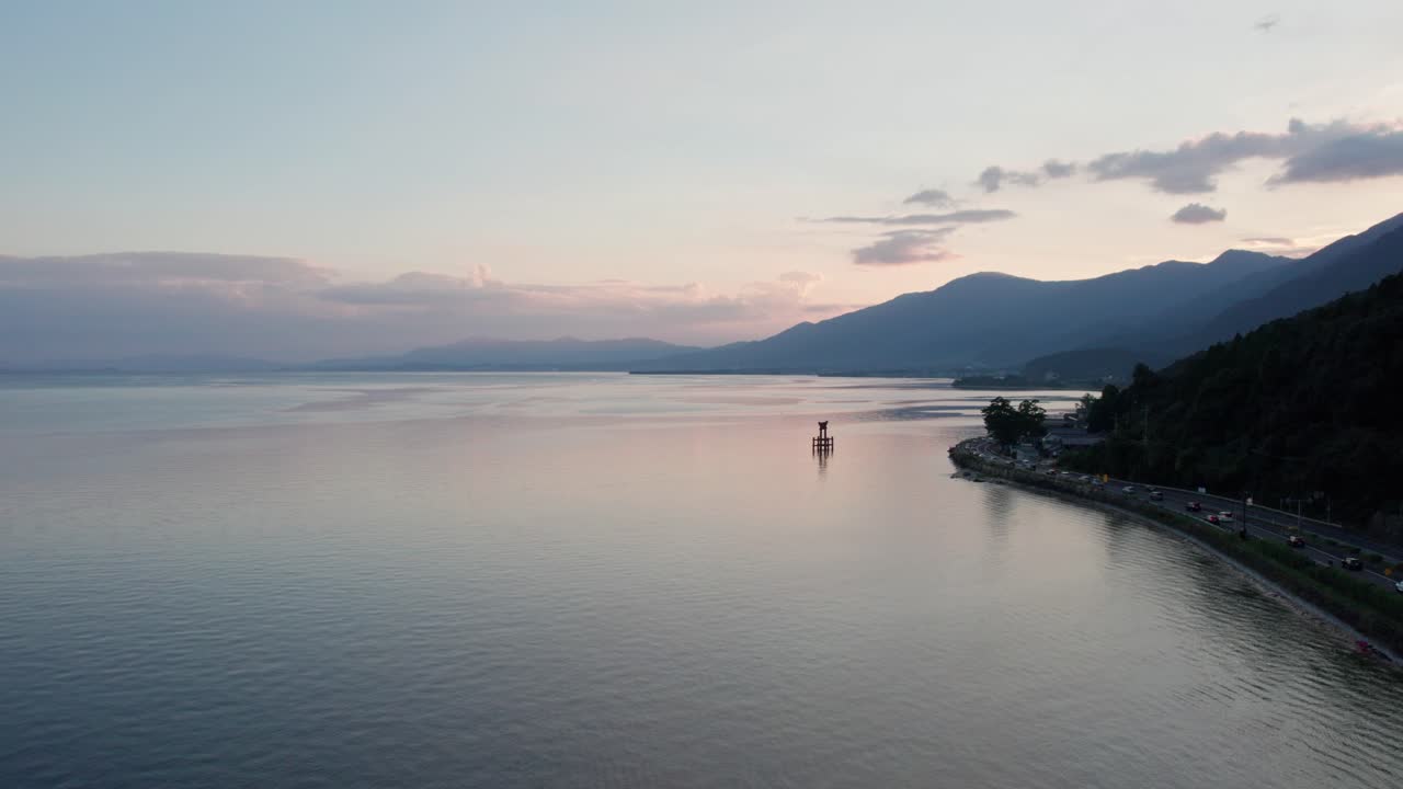 Drone reveals Orange Japanese Tori Gate in Lake, Natural mountain landscape of Shiga prefecture
