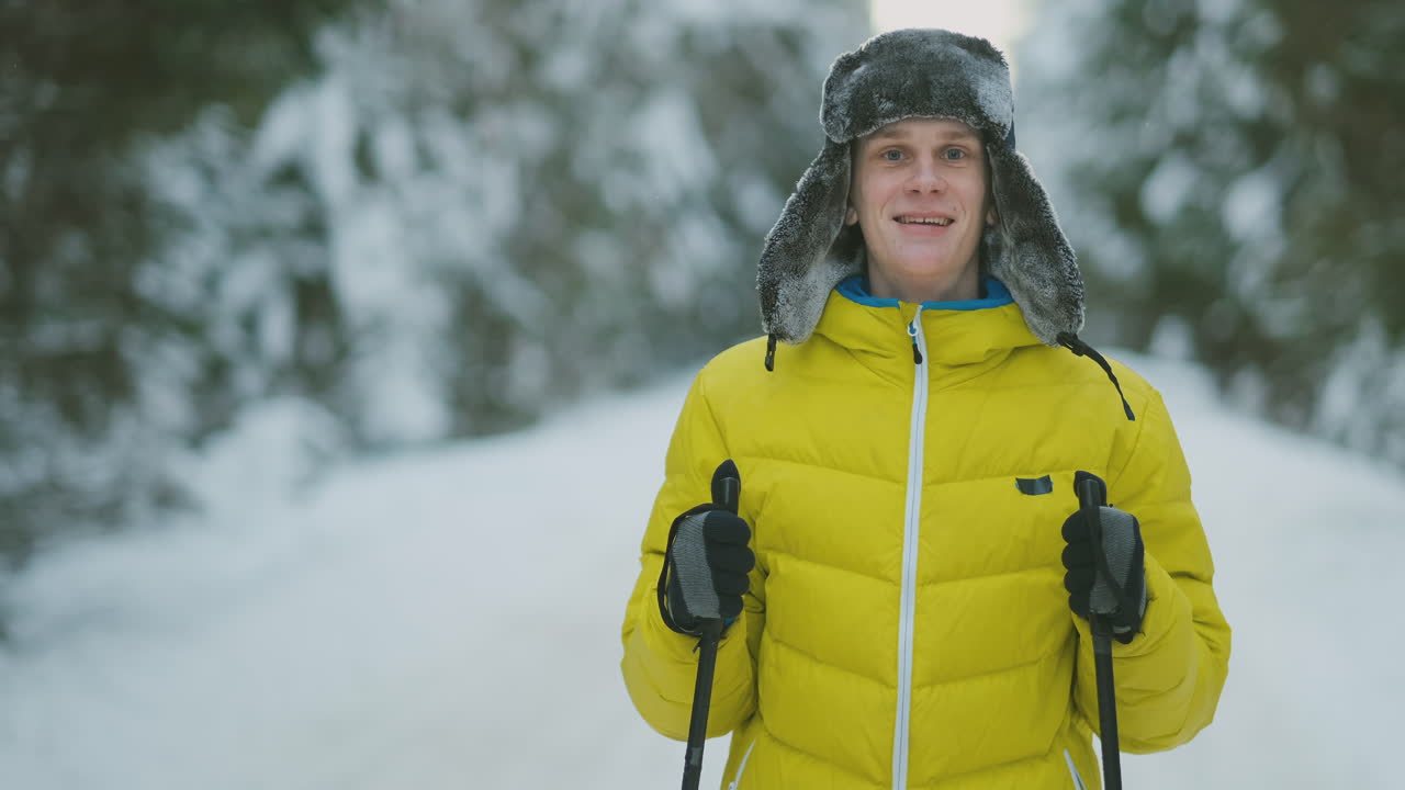 Uomo sorridente con gli sci e sua moglie che guardano qualcosa di curioso durante un'escursione in una foresta invernale