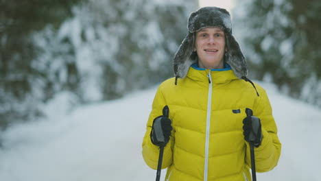 hombre sonriente con esquís y su esposa mirando algo curioso durante el viaje en el bosque invernal