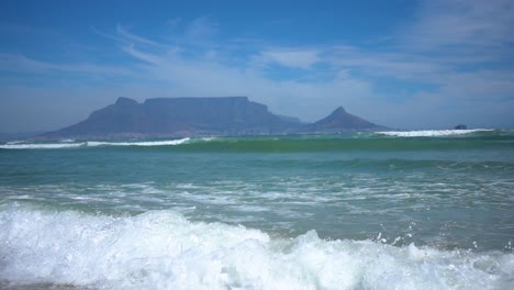 slowmotion of atlantic ocean waves and panning up to the table mountain in capetown in background