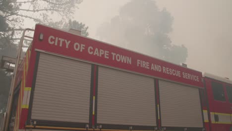 a firetruck from the city of cape town parked next to the scene of a wild fire in the forests near cape town