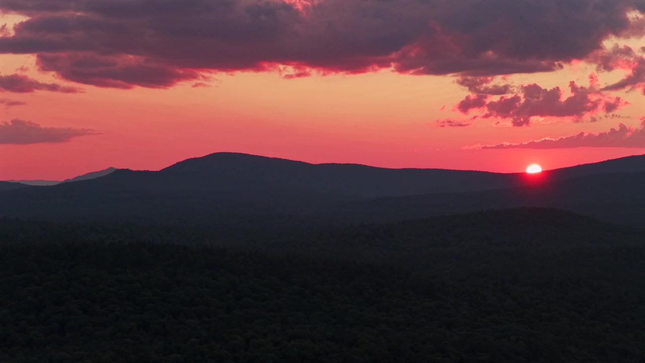 Levende solnedgang i den gyldne time, sol på horisontens skyer, Adirondack-bjergkæder, Schroon Lake, New York State, luftfoto fra drone af Adirondack High Peaks-lag, Mount Severance, Pharaoh Lake Wilderness, cirkel højre.