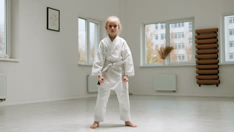 chica en kimono blanco en la clase de artes marciales