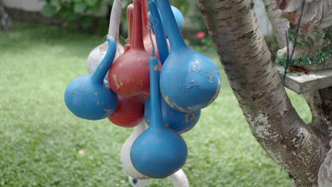 a bunch of blue, red, and white gourds hanging from a tree in a yard