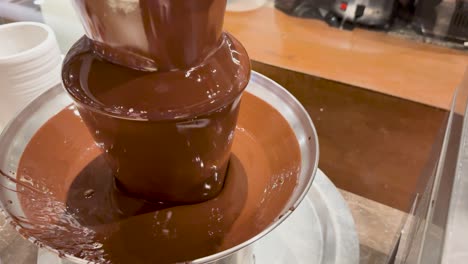 a chocolate fountain flows smoothly in a buffet setting, creating a rich, indulgent atmosphere with warm lighting