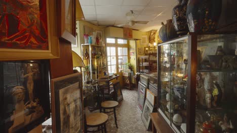 wide angle view of glass showcases in antique store across from paintings and vases