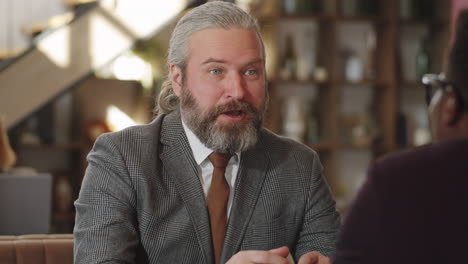 senior businessman shaking hands and talking with colleague in cafe