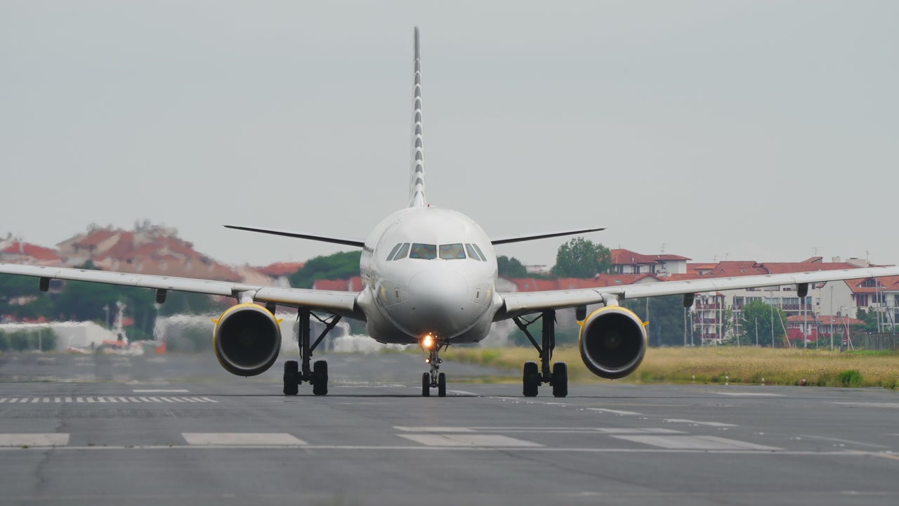 Jet commerciale in rullaggio frontale sulla pista con tempo coperto