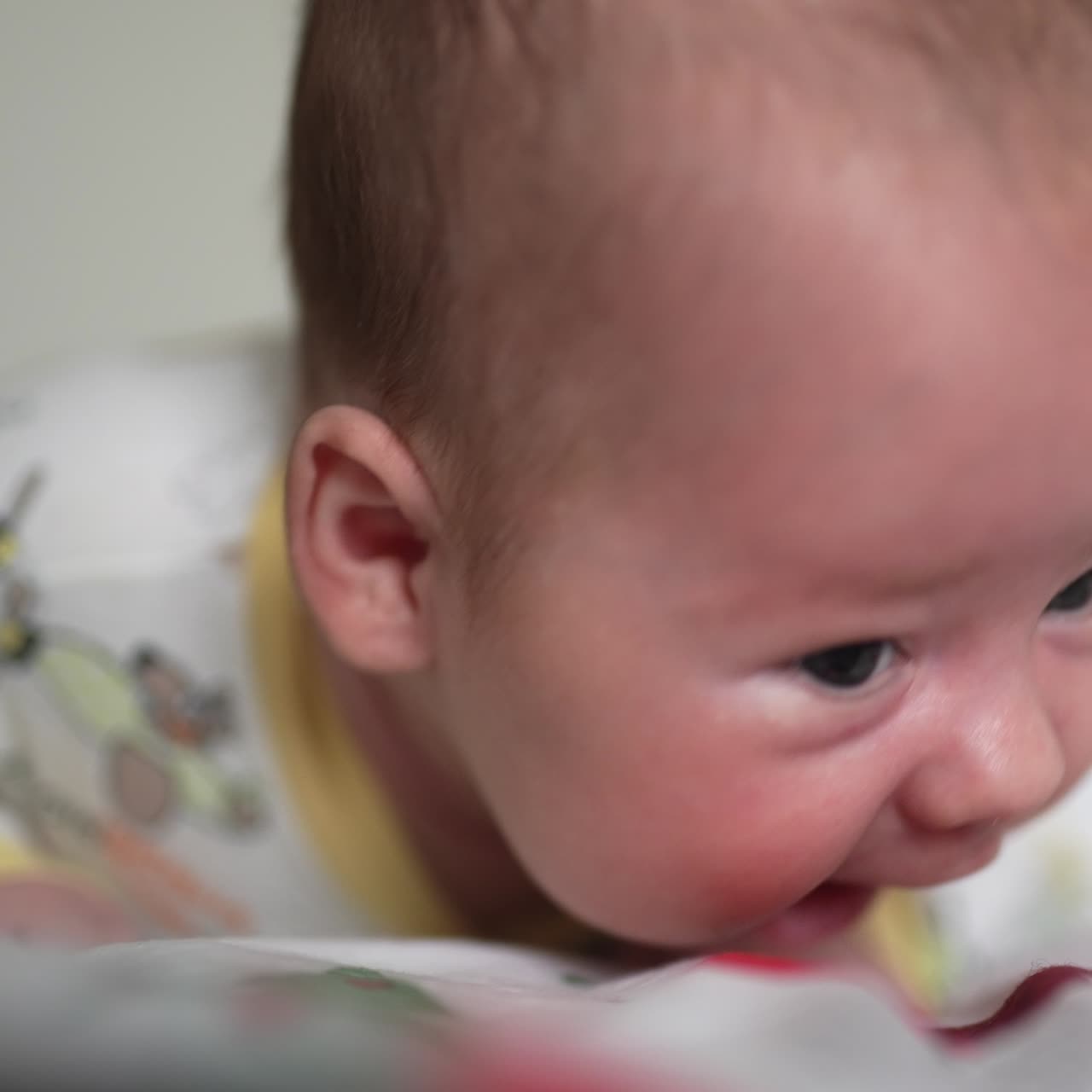 Beautiful Caucasian child lying on his belly. Curious baby trying to keep his head up and look around. Close up