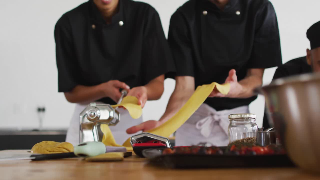 grupo diverso de chefs preparando platos y sonriendo en una cocina