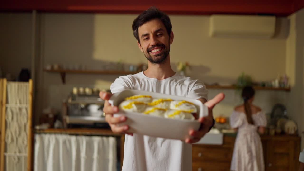 hombre sonriente sosteniendo un plato de pasteles frescos en una panadería