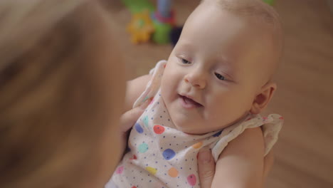 loving mother kissing baby daughter and making child smile