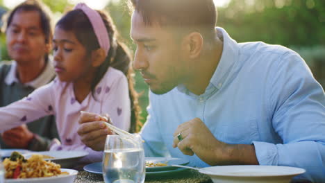 Young man using chopsticks to eat chinese food