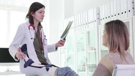 doctor examines x-ray and patient's leg brace during medical consultation