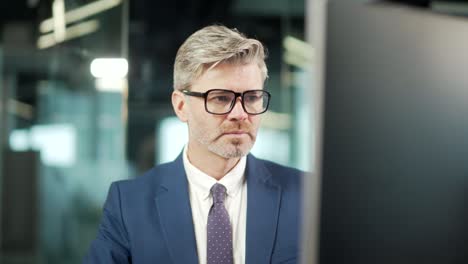 retrato hombre de negocios pensativo trabajando en una computadora pc en un escritorio de oficina moderno. confiado centrado pensativo hombre de negocios empleado en traje interior