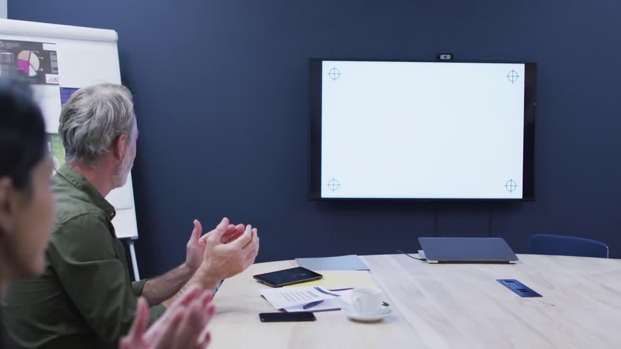 diversos colegas de negocios sentados mirando la pantalla y aplaudiendo en la reunión de la oficina
