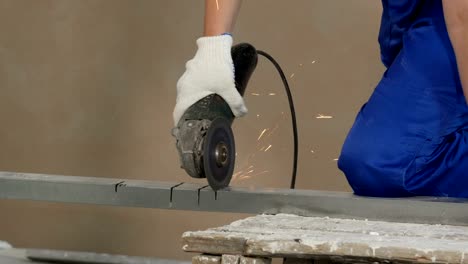 builder works with circular abrasive cutoff saw grinding machine and sparkles at construction site