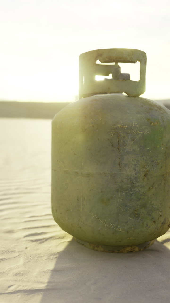 Vieille bouteille de gaz patinée abandonnée sur une plage de sable