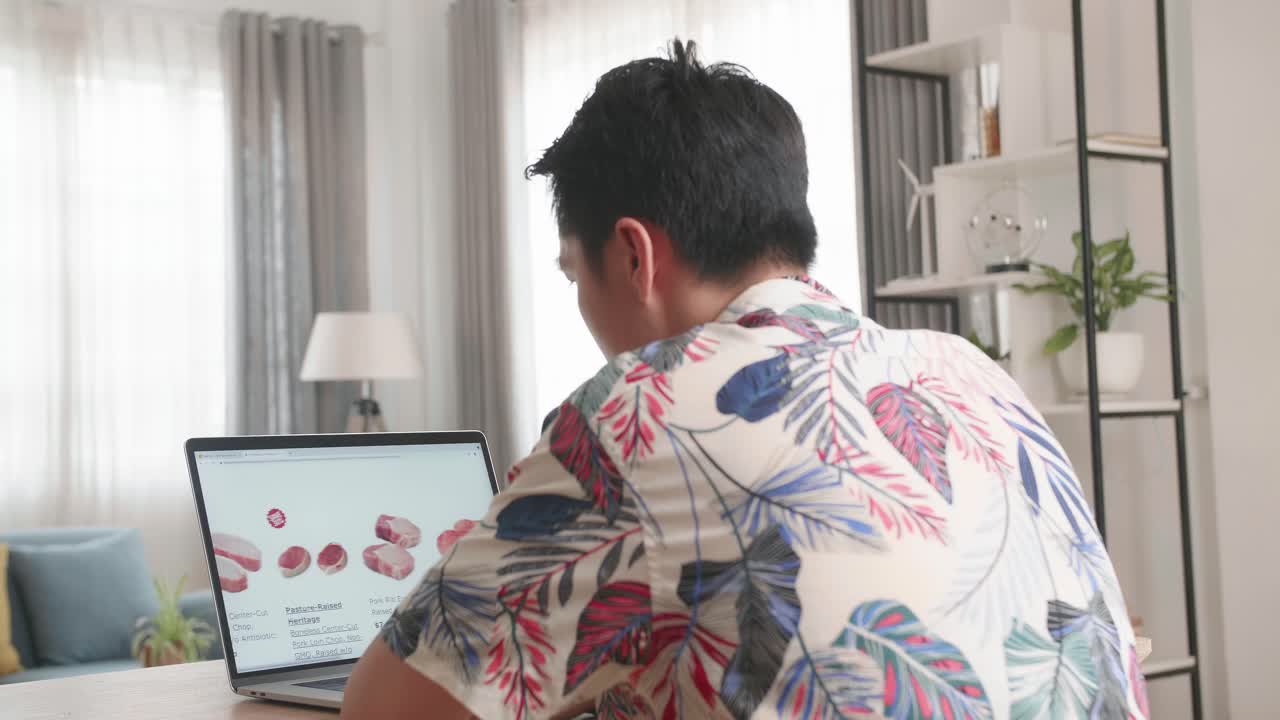 Asian Man Using Laptop Computer Buys In Internet Shop. Male Selects Beef In Grocery Online Store