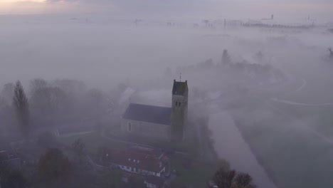 rural town hichtum covered in dense fog during sunrise, aerial