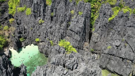 hidden beach, el nido, palawan island, philippines. drone aerial view revealing exotic lagoon and people snorkeling
