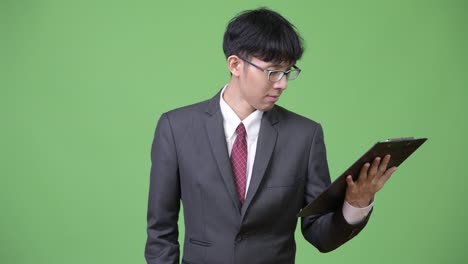 joven empresario asiático leyendo y pensando con el clipboard