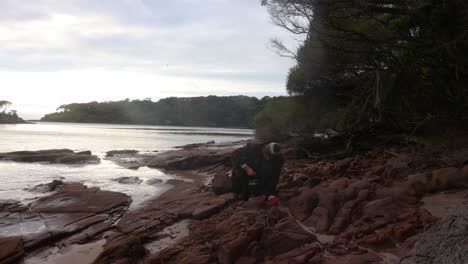 A-bushman-boils-up-some-water-on-a-gas-cooker-on-the-shores-of-a-nsw-coastal-bay