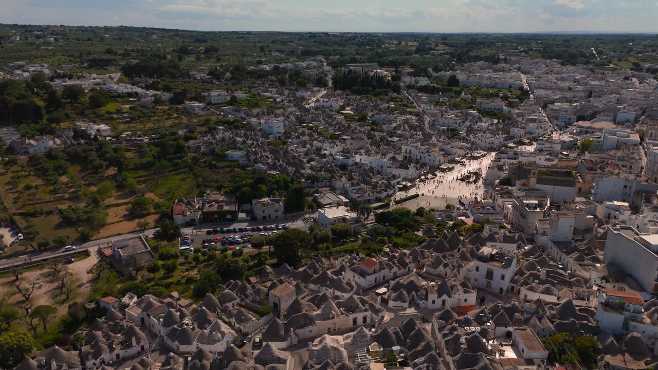 Panoramic drone shot showing Alberobello Trulli layout and surrounding Apulian countryside. Italy.