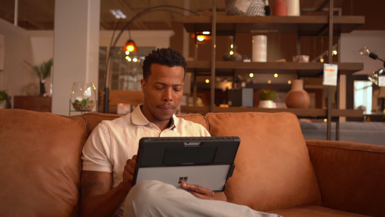 Man using tablet on leather couch in modern living room