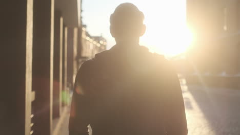 young european man with glasses walking through city at golden hour with black clothes and cars in background (hamburg, germany)