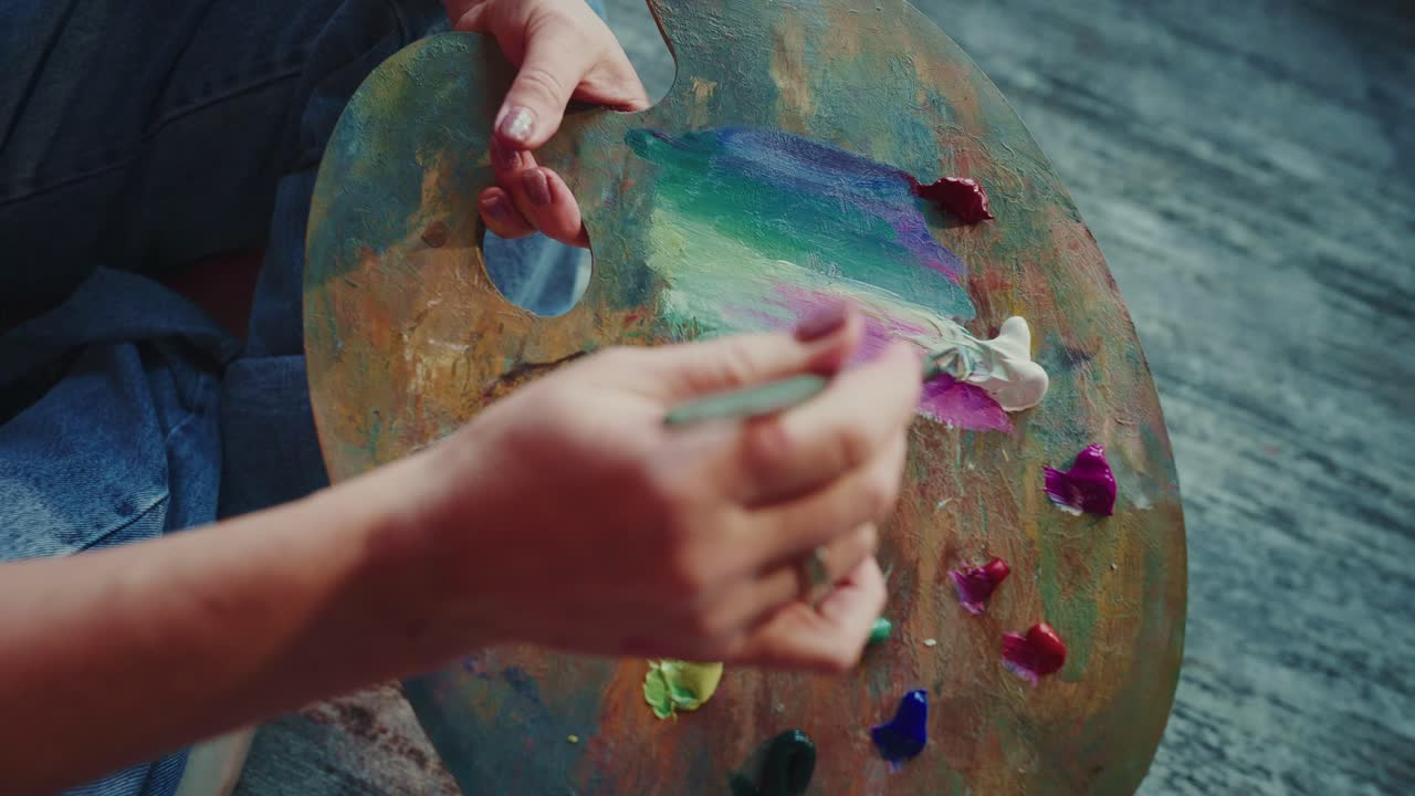 Artista che mescola vivaci colori a olio su una tavolozza di legno