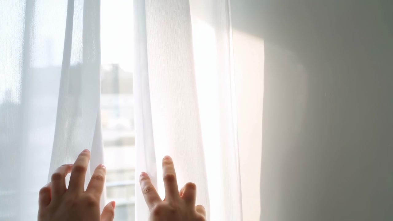 Soft Morning Light Through Sheer Curtain, Hands Parting Fabric At City Window, Distant Rooftop Silhouettes