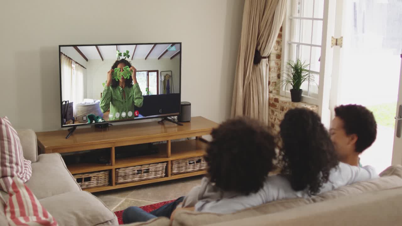 Famiglia afroamericana a casa che usa la smart TV per fare una videochiamata nel giorno di San Patrizio.