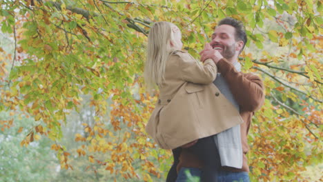 Vater-Trägt-Tochter-Vor-Dem-Hintergrund-Der-Herbstblätter-Auf-Einem-Spaziergang-Durch-Die-Landschaft