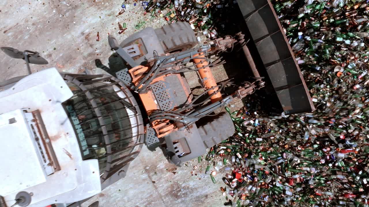 포크리프트 발굴기는 창고에서 유리를 잡고 있습니다. 무거운 기계는 유리를 잡는 부착 장치가 장착된 긴 팔을 가지고 있습니다.  ⁇ 빛의 날에 위에서 볼 수 있습니다. 유리 저장 및 재활용 개념