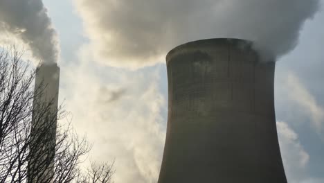 torres de enfriamiento de plantas de energía combustible fósil humo contaminación del aire retroiluminada por el amanecer