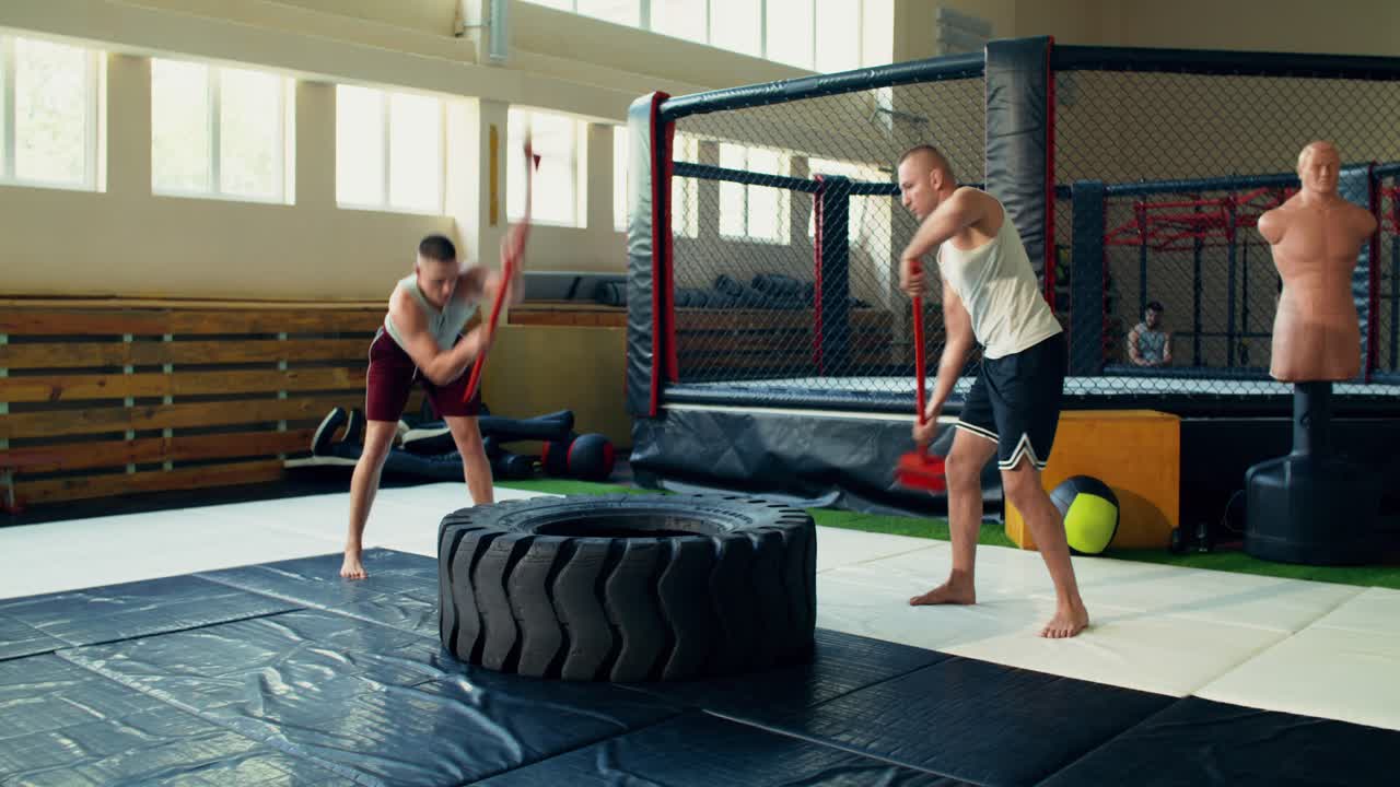Spor salonunda çekiç ve lastikle egzersiz yapan adamlar