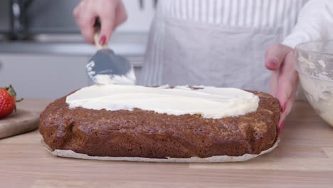 pastry chef spreading icing on top of carrot cake using spatula