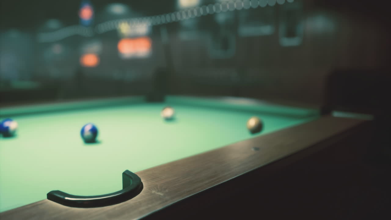 Pool table with colorful balls in dimly lit bar setting at night