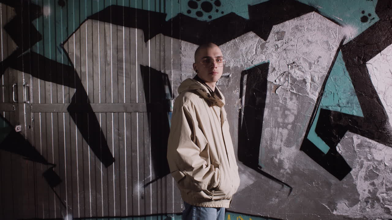 Young man in street style clothing in front of graffiti art