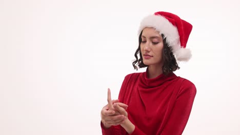 young woman in santa hat and red dress interacting with her hands on white background