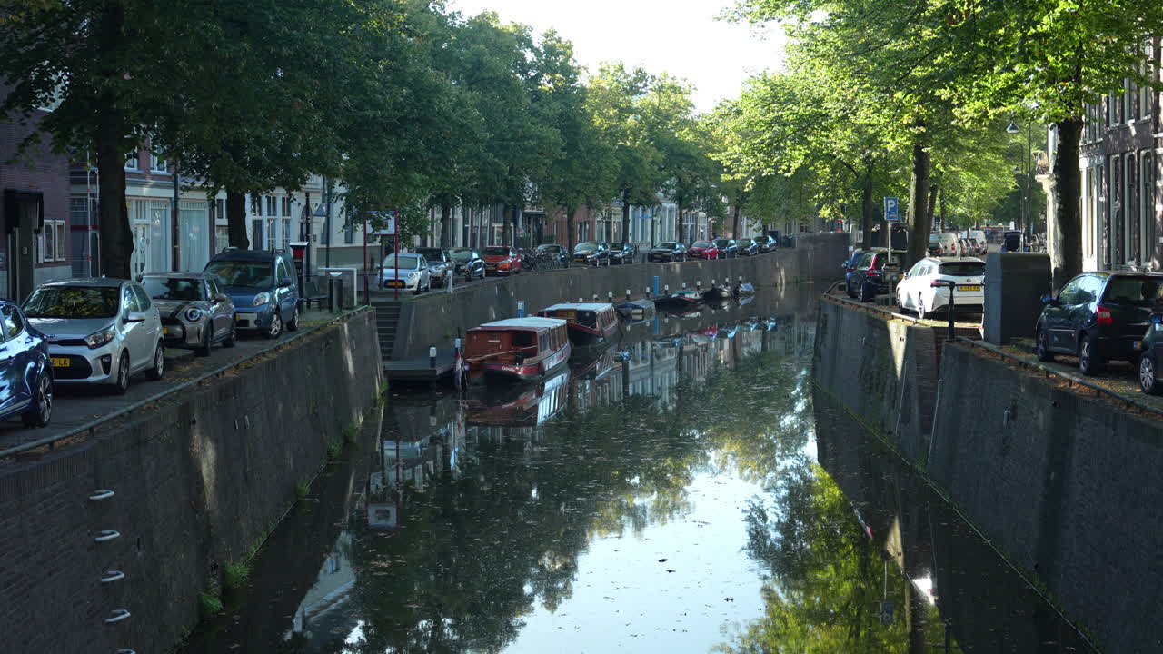 네덜란드 구다 시의 운하 근처에 주차 된 자동차와 함께 웨스트 헤이븐과 오스트 헤이븐 거리