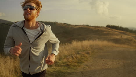 smiling sportsman running on mountain road. male athlete jogging outdoor