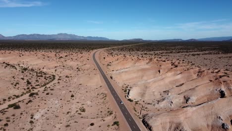 One-lone-car-drives-remote-badlands-highway-in-mountain-landscape,-ARG