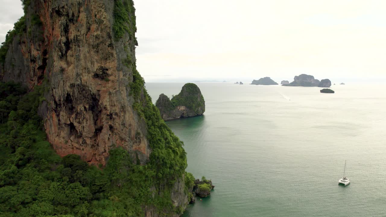 Railay's Bat Cave with Tall Rocky Limestone Cliffs and Ocean Views of Tropical Islands on the Horizon from an Aerial Drone