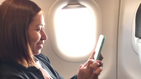 la felicidad de una chica asiática usando un teléfono inteligente y sonriendo en el avión.