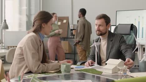 Woman-And-Man-Talking-About-Renewable-Energy-Project-In-The-Office