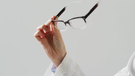 video of midsection of caucasian female doctor holding glasses, with copy space