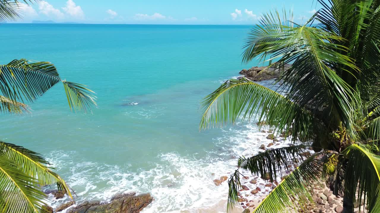 Filmagem aérea com drone de uma praia isolada em Koh Lanta, Tailândia, com uma costa rochosa, palmeiras e água azul turquesa cristalina, ideal para mergulho, snorkel e conceitos de viagens na natureza tropical