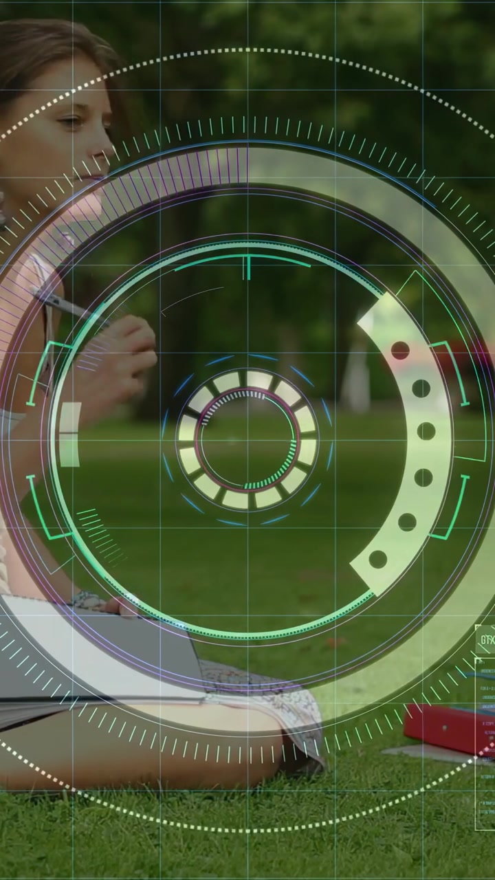 Video verticale: Donna che studia sull'erba, inizia a scrivere su un quaderno, si ferma mentre un HUD esegue una scansione.